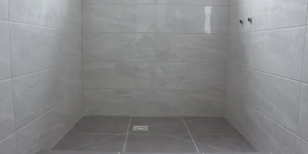 Modern shower room after renovation Sideboard drain in the floor and addition for faucets in the wall Gray tiles on the floor and walls